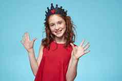 女孩卷曲的头发皇冠头红色的衣服生活方式蓝色的背景