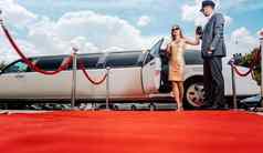 司机帮助贵宾女人明星豪华轿车红色的地毯
