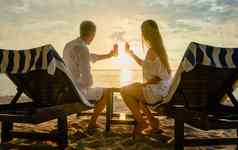 夫妇喝鸡尾酒海滩假期度蜜月热带地区