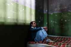 抑郁年轻的男人。坐着床垫黑暗监狱细胞监护权