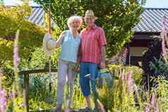 肖像活跃的高级夫妇持有园艺工具花园