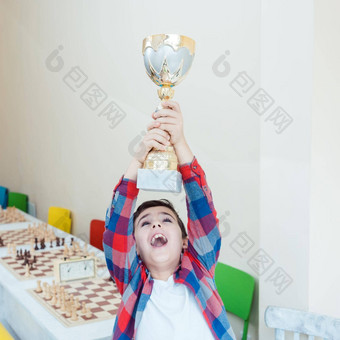 男孩显示奖杯赢得了国际象棋比赛