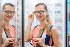 年轻的女人验光师商店检查镜子