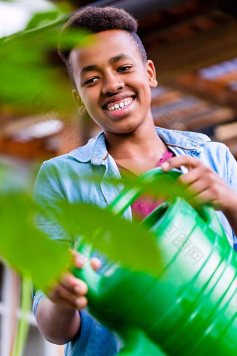 年轻的非洲<strong>男孩浇水</strong>植物花园