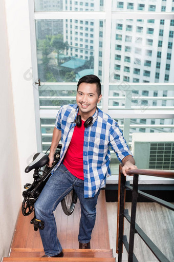 年轻的亚洲男人。携带<strong>折叠自行车</strong>楼梯公寓