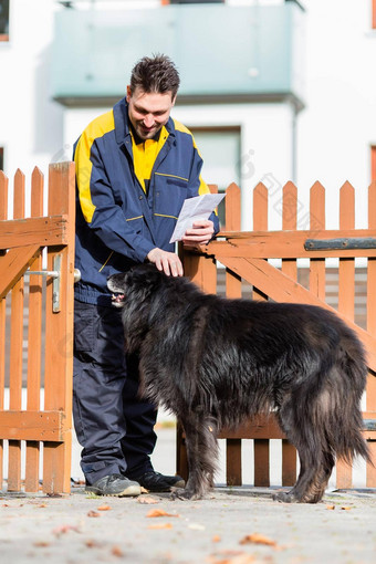 大黑色的狗欢迎邮递员花园门