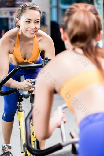 年轻的运动型女人骑车室内健身房骑自行车