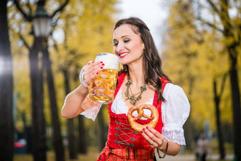 女孩传统的巴伐利亚试图喝啤酒巨大的杯子