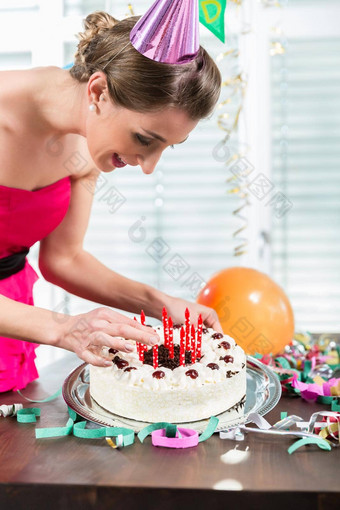 肖像美丽的女人微笑把红色的蜡烛蛋糕