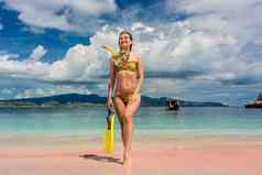 美丽的年轻的女人持有浮潜设备粉红色的海滩