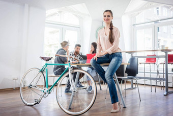 自信年轻的女人坐着桌子上通勤自行车
