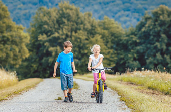 男孩女孩走骑自行车污垢路径