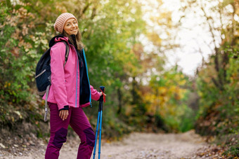 徒步旅行者女孩站宽小道山背包客粉红色的夹克森林健康的健身生活方式在户外