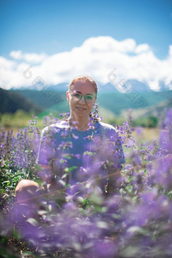 快乐年轻的女人美丽的野生粉红色的紫色的花场