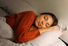 漂亮的年轻的女人睡觉拥抱枕头床上晚上
