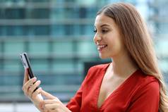 肖像美丽的休闲业务女人发送消息移动电话聊天应用程序现代摩天大楼背景