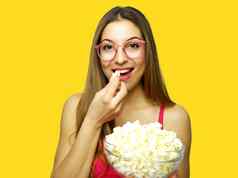 快乐快乐的女人吃流行玉米黄色的背景女孩持有大玻璃碗电影部分流行玉米