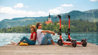 年轻的夫妇电踏板车现代生态运输探索绿色国家斯洛文尼亚假期绿色生态能源概念发射温暖的阳光过滤器