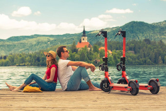 年轻的夫妇电踏板车现代生态运输探索绿色国家斯洛文尼亚假期绿色生态能源概念发射温暖的阳光过滤器