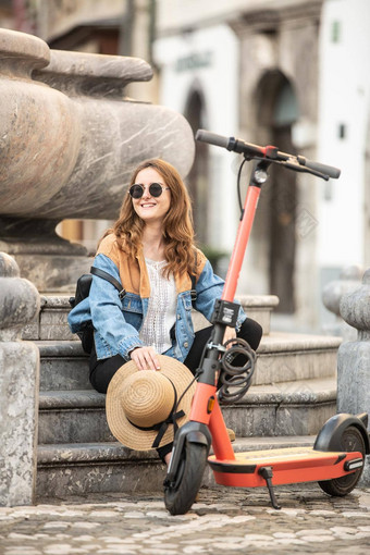 旅行者探索卢布尔雅那的中世纪的历史城市环境友好的电踏板车女旅游探索城市中心坐着休息喷泉的楼梯