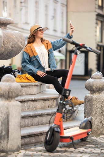 年轻的女人坐着楼梯历史建筑城市中心采取图片电话女旅行者探索卢布尔雅那的小镇电踏板车夏天休闲