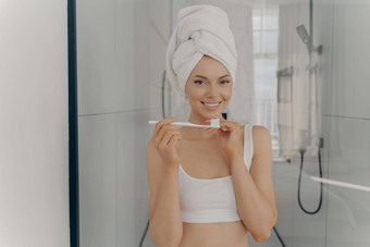 快乐美丽的夫人健康的完美的微笑刷牙牙齿站浴室图片