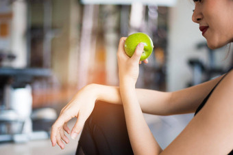 体育女人坐着吃绿色苹果健身培训健身房食物水果营养概念放松清洁食物概念医疗保健锻炼锻炼主题