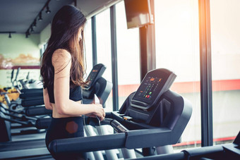 亚洲女人聪明的电话锻炼强度培训健身健身房跑步机放松技术概念体育锻炼健康护理主题快乐舒适的情绪