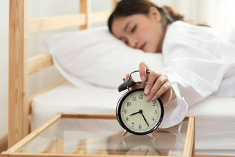 亚洲年轻的美女人把报警时钟早....晚些时候时钟懒惰的工作假期卧室床上时间概念放松人生活方式累了工人