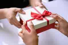 特写镜头手给礼物盒子红色的丝带圣诞节一天一年节日男人。给惊喜女人假期事件令人惊讶的礼品盒约会结束一年聚会，派对