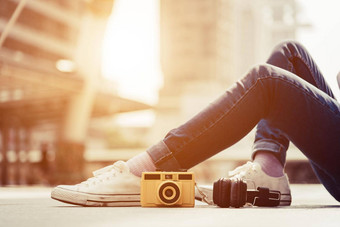 女人腿穿牛仔裤休息放松中间城市古董相机立体声耳机元素时尚现代技术概念快乐生活少年主题生活方式城市