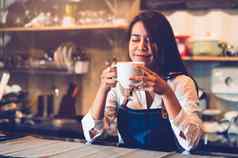 美亚洲女咖啡师持有杯咖啡品尝酿造咖啡咖啡馆餐厅背景女服务员闻咖啡自助餐厅食物喝概念人生活方式