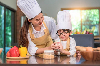 亚洲妈妈。帮助可爱的男孩喝牛奶玻璃首页厨房老板烹饪统一的人生活方式快乐家庭在一起概念钙蛋白质牛奶营养