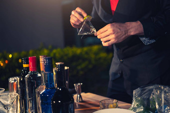 专业酒保准备新鲜的石灰柠檬水鸡尾酒喝酒玻璃冰晚上酒吧泡吧计数器占领人生活方式概念户外背景
