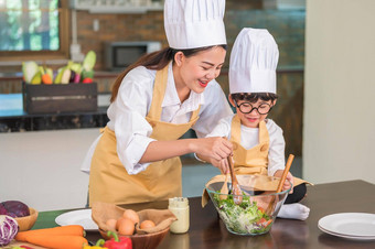 快乐美丽的亚洲女人可爱的男孩眼镜准备烹饪厨房首页人生活方式家庭自制的食物成分概念泰国人生活