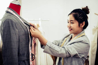 亚洲女时尚设计师女孩使适合正式的西装统一的衣服人体模型模型时尚设计师时尚的展厅缝纫裁缝概念有创意的裁缝设计师