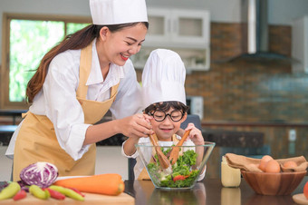 快乐美丽的亚洲女人可爱的男孩眼镜准备烹饪厨房首页人生活方式家庭自制的食物成分概念泰国人生活