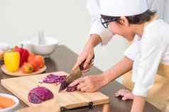 特写镜头妈妈。手切片紫色的卷心菜木董事会可爱的亚洲男孩妈妈。准备烹饪首页厨房人生活方式家庭自制的食物成分概念