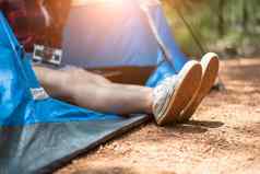 关闭女人strecthing脚鞋自然背景旅游女人休息野营帐篷人生活方式概念假期假期主题相机元素
