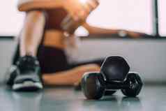 关闭哑铃锻炼女人生活方式锻炼健身房健身打破放松体育运动培训蛋白质摇瓶背景健康的生活方式健身运动员肌肉