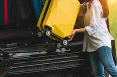亚洲女人提升黄色的手提箱运动型多功能车车旅行长周末旅行人生活方式运输概念女孩把行李车树干假期野营夏天时间