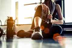 体育运动女人坐着休息锻炼锻炼健身健身房蛋白质摇喝水地板上放松概念强度培训身体构建主题温暖的很酷的语气