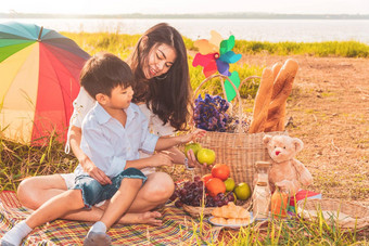 美丽的亚洲妈妈。儿子野餐复活节夏天聚会，派对草地湖山假期假期人生活方式快乐家庭生活概念泰国人
