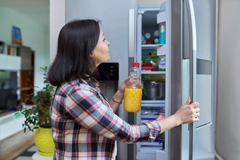 女人<strong>打开冰箱</strong>首页厨房持有瓶橙色汁