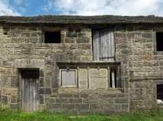 古老的被遗弃的石头小屋行农村建筑空窗户木门人行道上杂草丛生的草