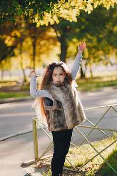 时尚的婴儿女孩一年穿靴子皮毛外套站公园相机秋天秋天季节