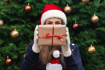 圣诞节礼物年轻的女孩穿圣诞老人老人他礼物使工艺纸红色的丝带背景圣诞节树