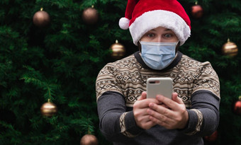 圣诞节在线祝贺你惊讶震惊了男人。穿圣诞老人他医疗面具会说话的电话朋友父母圣诞节树散景背景