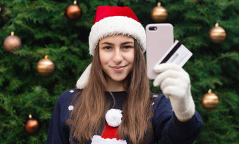 圣诞节在线购物年轻的女孩圣诞老人老人他蓝色的毛衣持有智能手机圣诞节冠状病毒