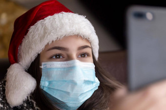 圣诞节在线年轻的女孩圣诞老人老人他医疗面具会谈智能手机视频调用朋友父母圣诞节冠状病毒
